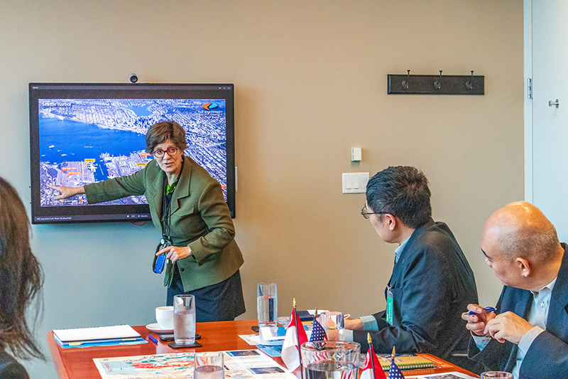 Stephanie Jones Stebbins points to an aerial map on a screen while meeting with representatives from the port of Singapore.