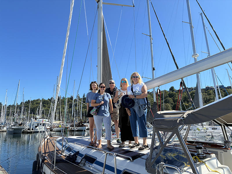 Four passengers pose with Captain Margaret Pommert before a chartered sail. 
