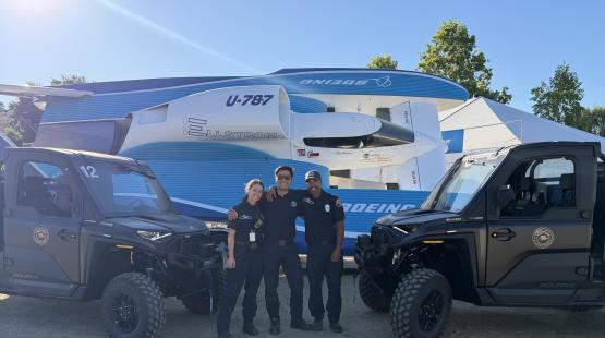 three port of seattle firefighters stand between two atvs and a trailer laoded hydroplane smiling