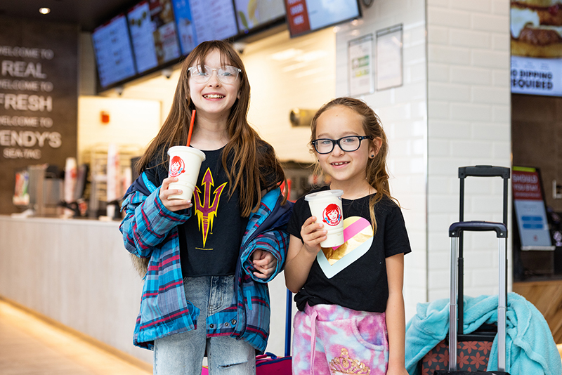 Two girls drinking Wendy's milkshakes.