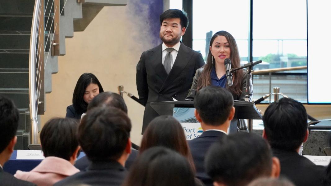 Commissioner Hasegawa speaking at a public event with Commissioner Sam Cho beside her