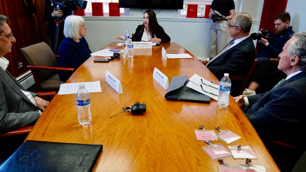 Commissioner Hasegawa sitting at a long table talking with elected state leaders