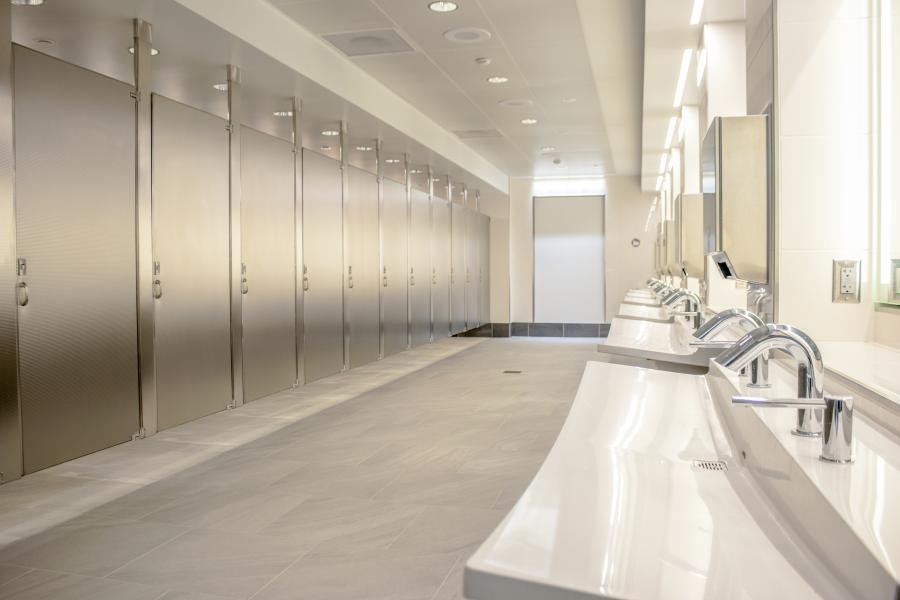 Empty restroom with stalls and sinks.