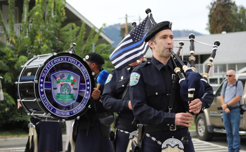 Officer playing the bagpipes, a drummer in the background.