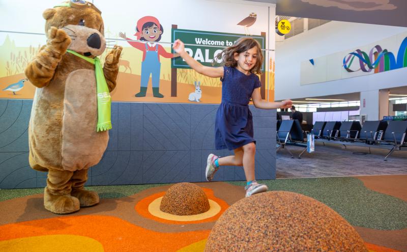 Child jumps from one mound to another while Jett the SEA otter looks on.
