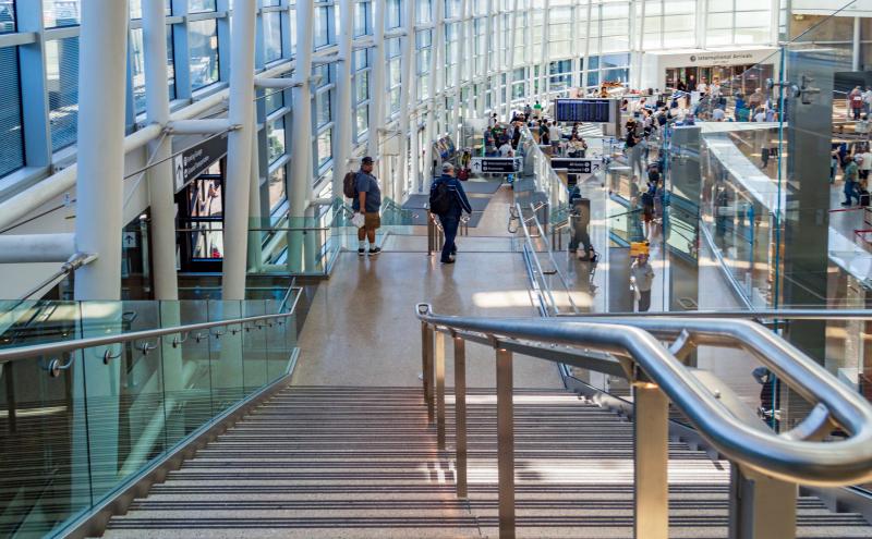 Stairs leading down to international arrivals area with large wall of windows.