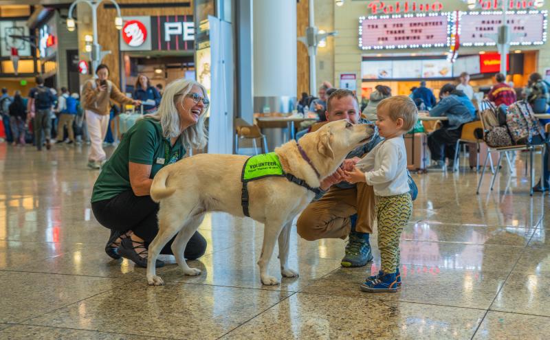 Travelers smiling and interacting with SEA Pup and Volunteer. 